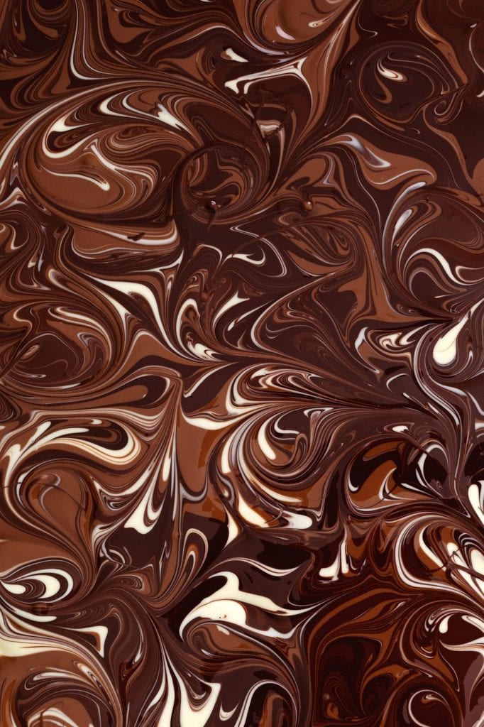 Melted white, milk and dark chocolate swirled in an intricate pattern.a