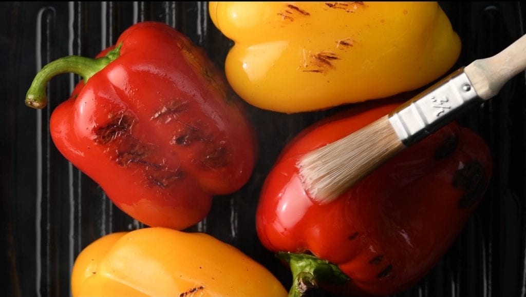 video Showreel displaying roasted peppers being brushed with oil, roasted tomatoes being turned on the griddle and salt being added to roasted aubergine.