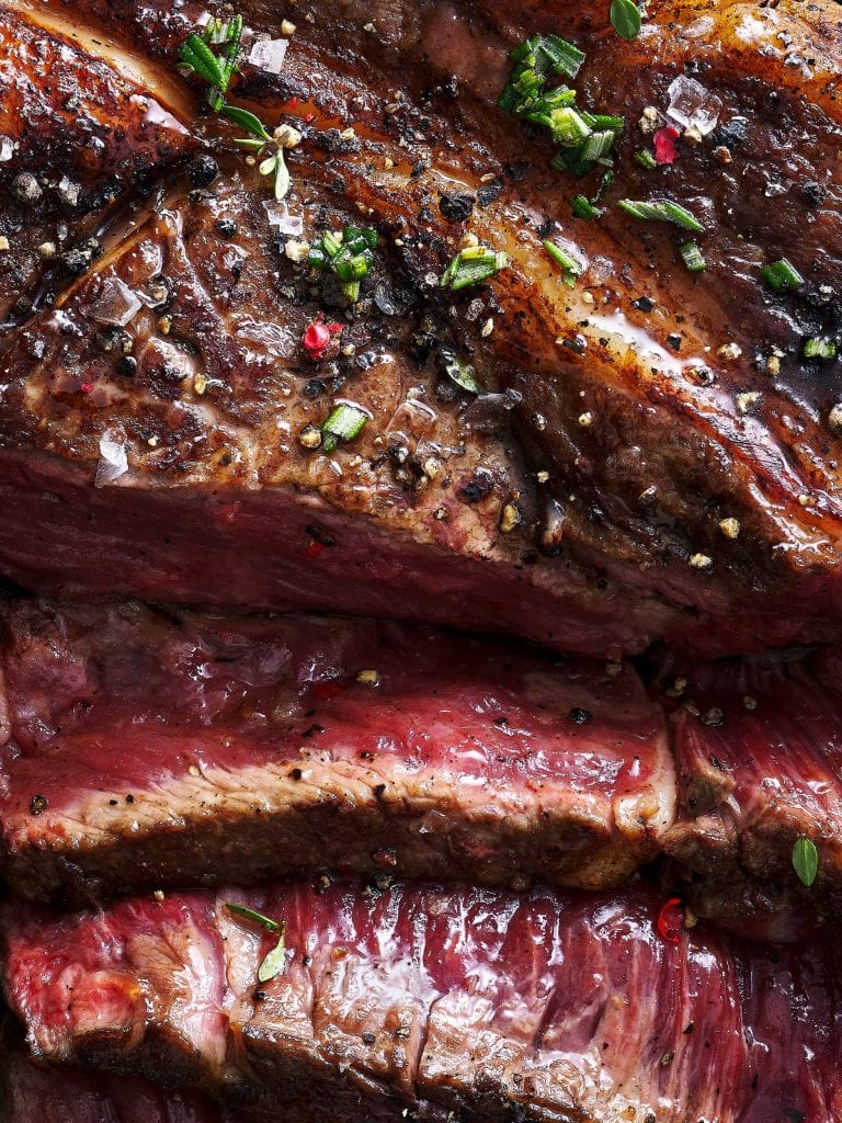 macro food photography of beef joint garnished with salt pepper and thyme