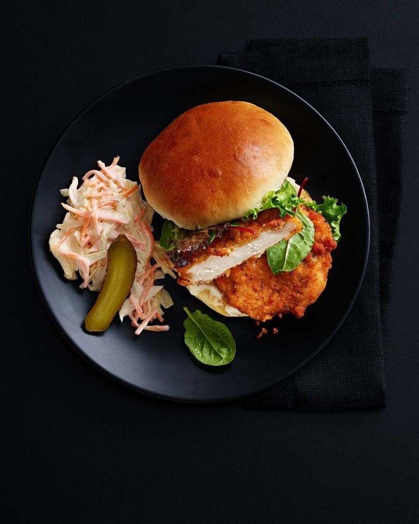 Shot for Marks And Spencer Hospitality Menus. Chicken burger with coleslaw and pickle. Graphic shot on black black with black background.