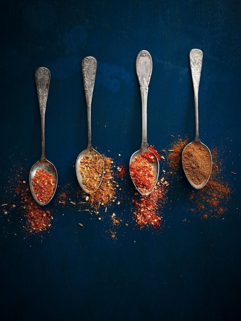 slimming world magazine various spices in silver spoons on dark blue background