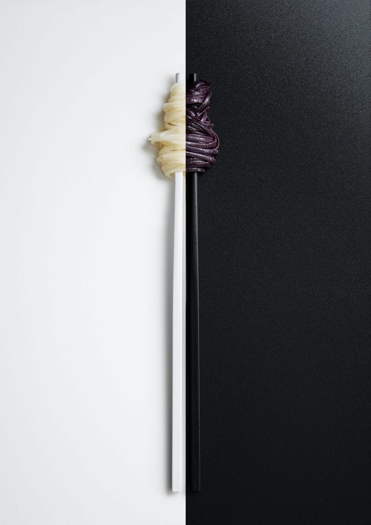 Black and white noodles on chopsticks